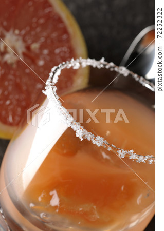 Salty dog with salt on the edge of the glass and cut grapefruit and bar spoon 72252322