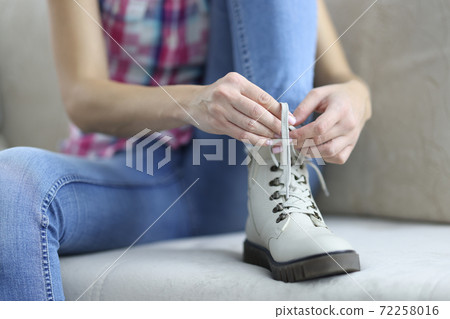 Woman tying shoelaces on new demi leather boots. Woman tying shoelaces on new demi leather boots. 72258016