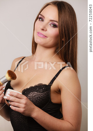 Woman in lingerie applying loose powder with brush 72258043