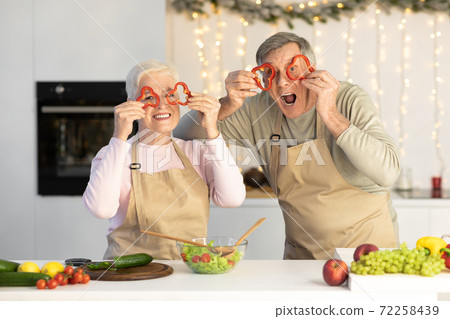 Elderly Spouses Having Fun Looking Through Vegetables Posing In Kitchen 72258439