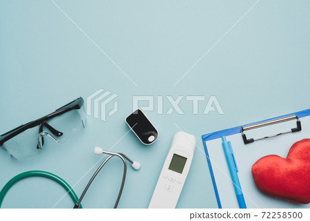 pulse oximeter and electronic thermometer and other medical supplies on a blue background pulse oximeter and electronic thermometer and other medical supplies on a blue background 72258500