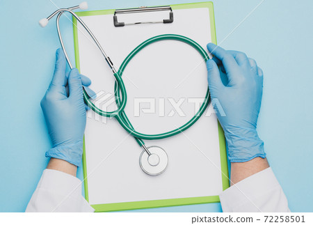 female doctor's hands in blue latex gloves holding a metal stethoscope 72258501