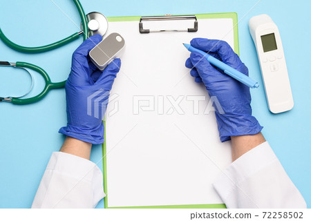 doctor's hands in blue medical gloves holds an electronic pulse oximeter 72258502