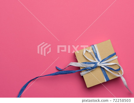 gift wrapped in brown kraft paper on a pink background 72258503
