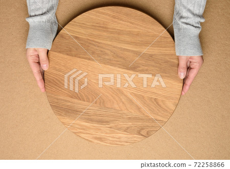 woman holding empty round wooden pizza board in hand 72258866