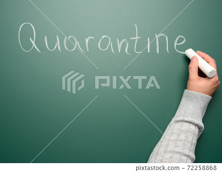 female hand writes the word quarantine in white chalk on a green chalk board female hand writes the word quarantine in white chalk on a green chalk board 72258868
