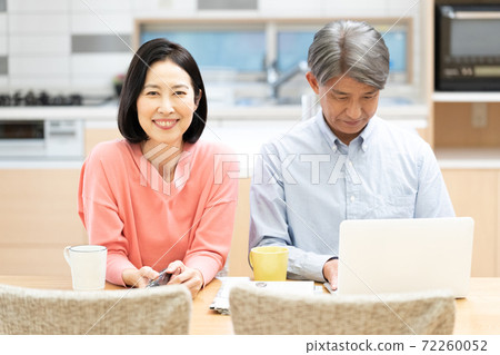A wife watching TV and a husband heading to a computer 72260052