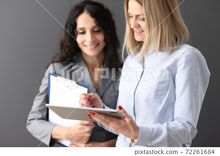 Businesswoman showing information to colleague on tablet and smiling Businesswoman showing information to colleague on tablet and smiling 72261684