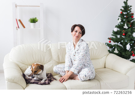 Happy young woman wearing pajama in living room with christmas tree. Holidays concept. Happy young woman wearing pajama in living room with christmas tree. Holidays concept. 72263256