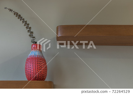 Dried flowers in beautiful ceramic red vase standing on wooden shelf. Dried flowers in beautiful ceramic red vase standing on wooden shelf. 72264529