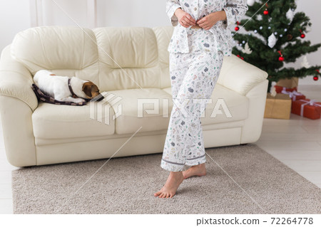 Close-up of woman wearing pajama in living room with christmas tree. Holidays concept. 72264778