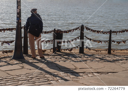 The back of Lonely young man standing on the river walk and looking at skyline. The back of Lonely young man standing on the river walk and looking at skyline. 72264779