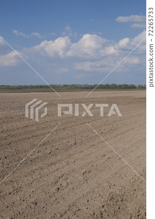 Beautiful sky over a plowed agricultural field. Agro-industrial landscape. A plowed farm field. Cultivated soil during the day. 72265733