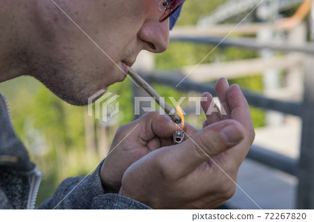 Close-up of young man smoking marijuana joint outdoors 72267820