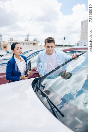 Looking at automobiles in car dealership 72268019