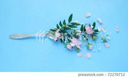 Various delicate flowers in a spoon on a blue background. 72270712