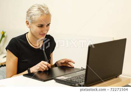 The girl learns to draw on a graphics tablet. Notebook. 72271504