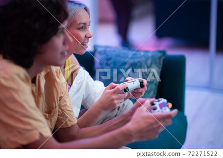 Smiling couple holding gamepads playing video game at home. Young people spending time together during self isolation on pandemic. 72271522