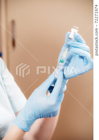 Woman doctor beautician picks up liquid into a syringe for injection rejuvenation 72271974