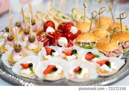 The buffet at the reception. Assortment of canapes on a table. Banquet service. Catering food, snacks with different types of cheese, ham, salami, prosciutto, shrimp, vegetables and fruits. Party 72272198