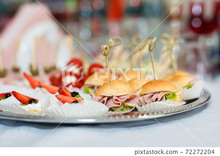 The buffet at the reception. Assortment of canapes on a table. Banquet service. Catering food, snacks with different types of cheese, ham, salami, prosciutto, shrimp, vegetables and fruits. Party The buffet at the reception. Assortment of canapes on a table. Banquet service. Catering food, snacks with different types of cheese, ham, salami, prosciutto, shrimp, vegetables and fruits. Party 72272204