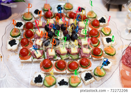 The buffet at the reception. Assortment of canapes on a table. Banquet service. Catering food, snacks with different types of cheese, ham, salami, prosciutto, shrimp, vegetables and fruits. Party The buffet at the reception. Assortment of canapes on a table. Banquet service. Catering food, snacks with different types of cheese, ham, salami, prosciutto, shrimp, vegetables and fruits. Party 72272206