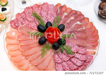 Different types delicacies of meat and cheese arranged in a plate over light background - selective focus 72272207