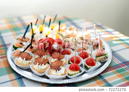 The buffet at the reception. Assortment of canapes on a table. Banquet service. Catering food, snacks with different types of cheese, ham, salami, prosciutto, shrimp, vegetables and fruits. Party 72272278