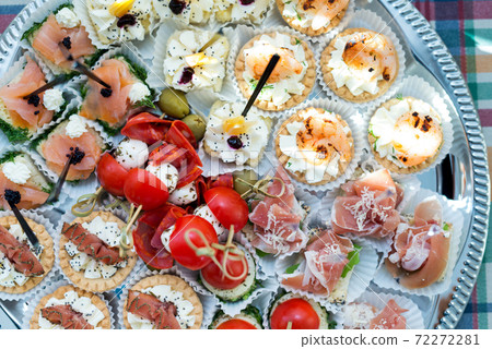The buffet at the reception. Assortment of canapes on a table. Banquet service. Catering food, snacks with different types of cheese, ham, salami, prosciutto, shrimp, vegetables and fruits. Party 72272281