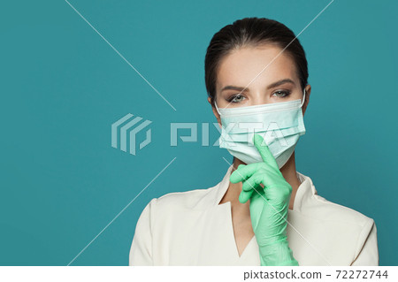 Portrait of doctor holding finger near lips on blue background. Medicine and cosmetology concept Portrait of doctor holding finger near lips on blue background. Medicine and cosmetology concept 72272744