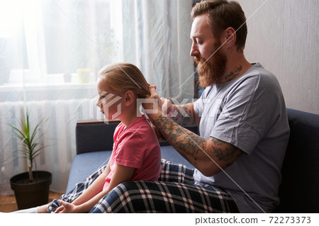 Father is combing his blonde daughter's hair Father is combing his blonde daughter's hair 72273373
