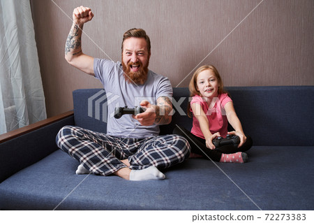 Father and his cute daughter gaming on console Father and his cute daughter gaming on console 72273383