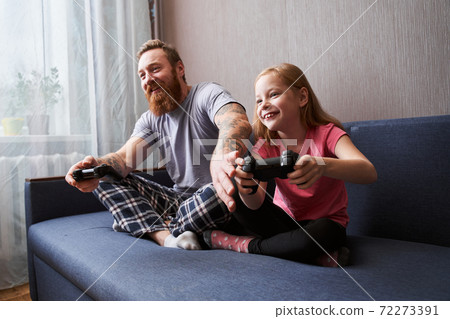 Father and his cute daughter gaming on console Father and his cute daughter gaming on console 72273391
