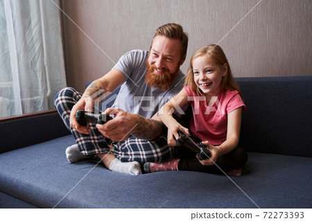 Father and daughter playing video games on console Father and daughter playing video games on console 72273393