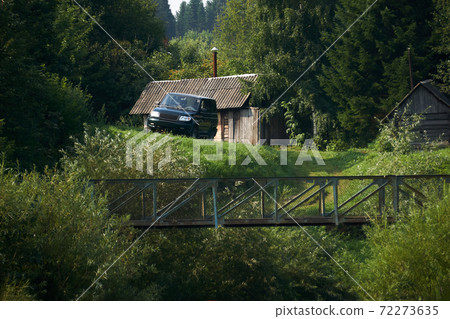 rural landscape, a lonely homestead in the forest - a log cabin, a bathhouse and an SUV on the edge of a ravine with a bridge rural landscape, a lonely homestead in the forest - a log cabin, a bathhouse and an SUV on the edge of a ravine with a bridge 72273635