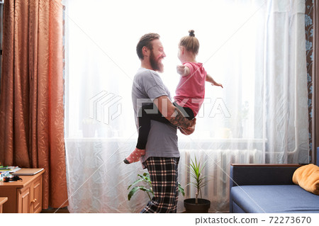 Father carrying his pretty daughter at his arms Father carrying his pretty daughter at his arms 72273670