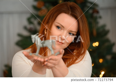 Beauty portrait of redhead caucasian woman holding generic wooden toy Beauty portrait of redhead caucasian woman holding generic wooden toy 72273794