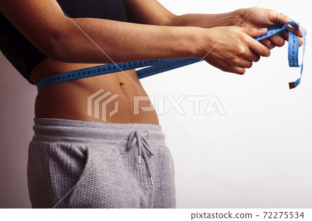 woman measuring waist with tape on knot, african tan isolated woman measuring waist with tape on knot, african tan isolated 72275534