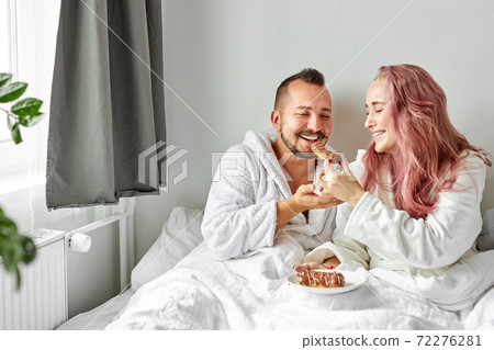 joyful couple eating eclairs in the morning 72276281
