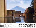 Beautiful woman enjoy onsen (mineral hot bath) in morning and seeing view of Fuji mountain in japan 72276635