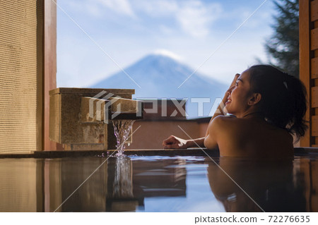 Beautiful woman enjoy onsen (mineral hot bath) in morning and seeing view of Fuji mountain in japan 72276635