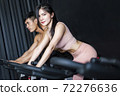 Young woman and friends on fitness bike in gym during workout 72276636