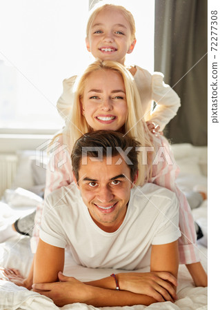 beautiful caucasian family consisted of woman man and child smile at camera lying on bed beautiful caucasian family consisted of woman man and child smile at camera lying on bed 72277308