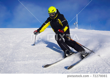 Skier skiing downhill in mountains 72278081
