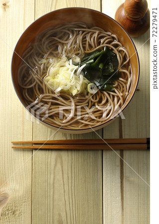 A simple kake soba topped with chopped green onions and wakame seaweed and a gourd-shaped shichimi bowl (overhead view) A simple kake soba topped with chopped green onions and wakame seaweed and a gourd-shaped shichimi bowl (overhead view) 72279471