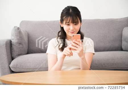 一個女人看著智能手機在一張矮桌 一個女人看著智能手機在一張矮桌 72285734