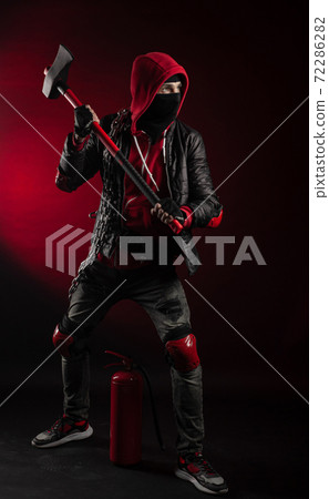 a man in a Balaclava and hoodie with an axe and a fire extinguisher the image of a Protestant 72286282