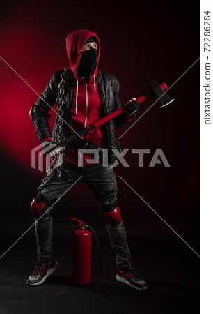 a man in a Balaclava and hoodie with an axe and a fire extinguisher the image of a Protestant 72286284