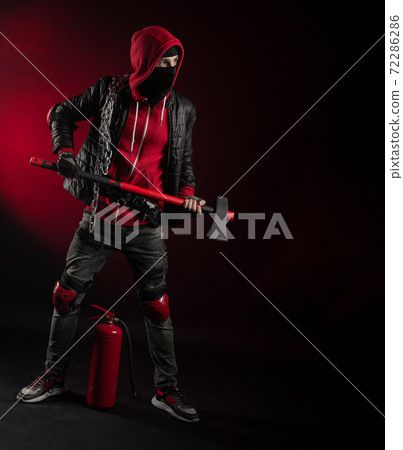 a man in a Balaclava and hoodie with an axe and a fire extinguisher the image of a Protestant 72286286