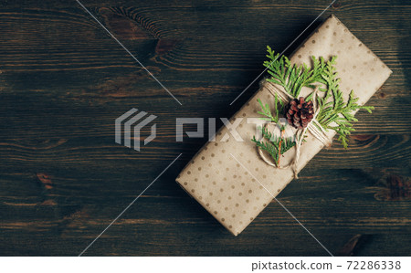 Gift box wrapped in craft paper and decorated with green cypress branch Gift box wrapped in craft paper and decorated with green cypress branch 72286338